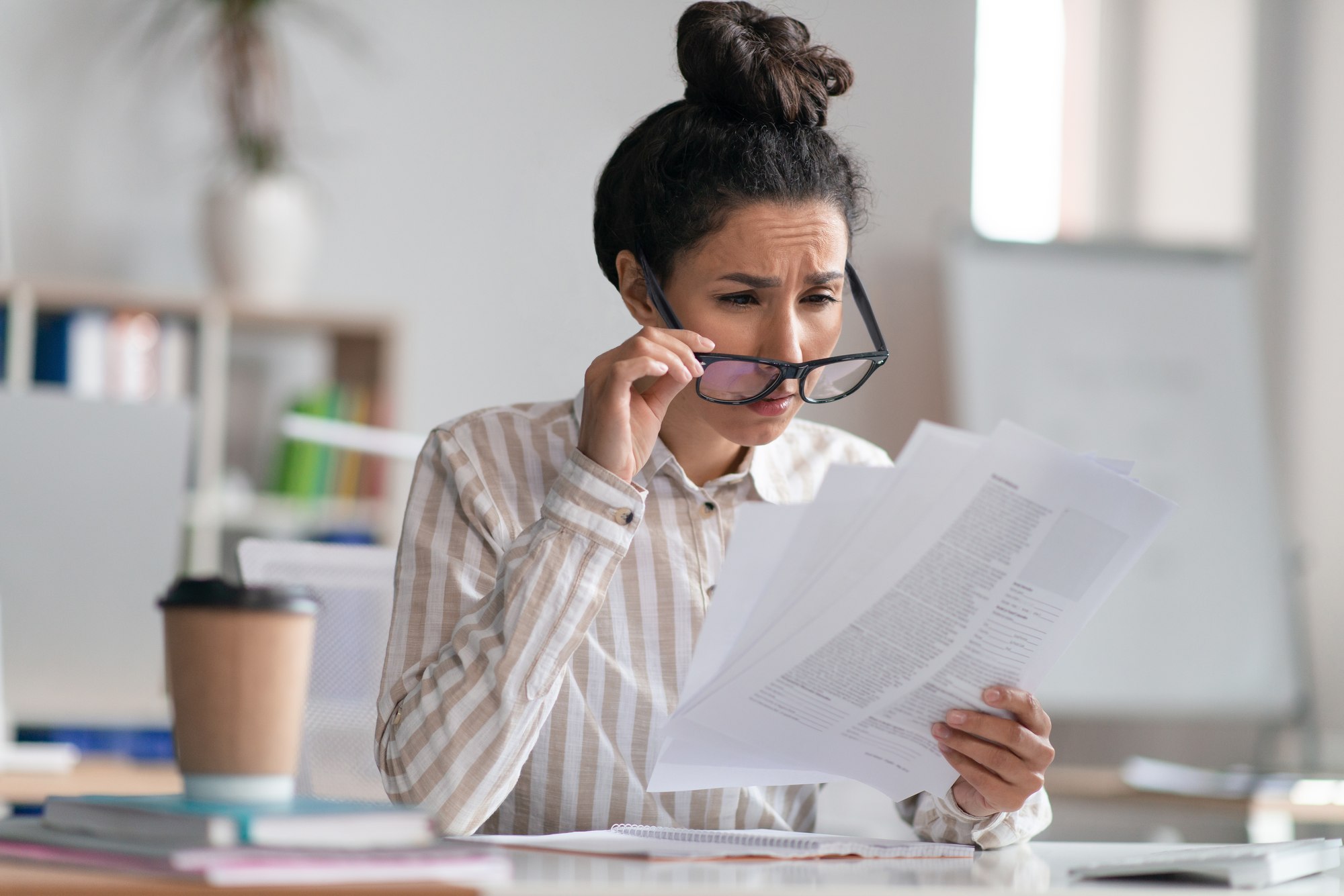 A woman squinting to read fine print, a common sign of uncorrected nearsightedness